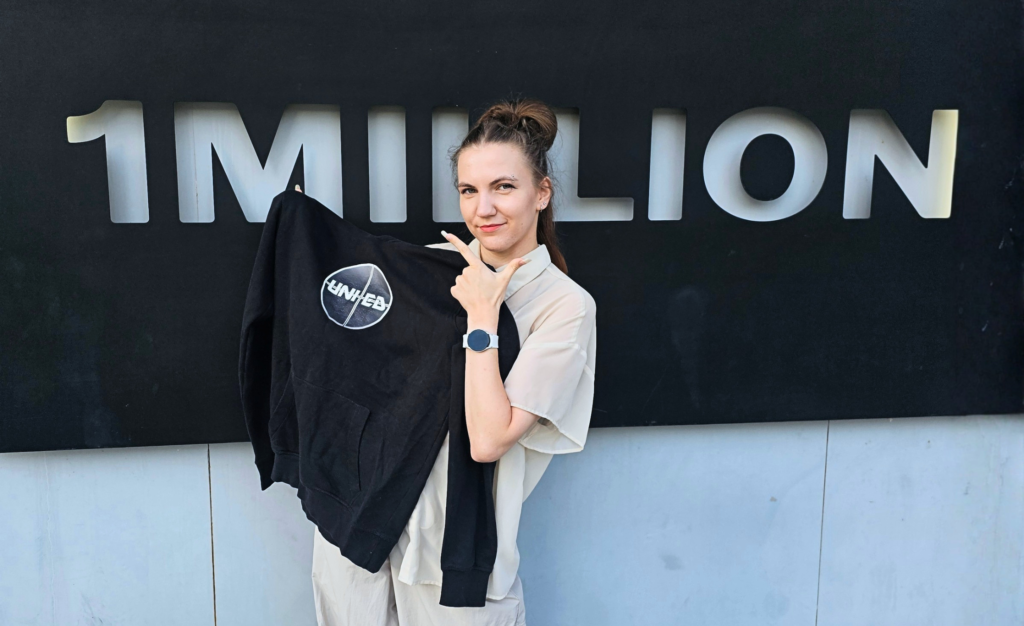 UNI+ED juhendaja Soulis 1MILLION Dance Studio ees, hoides käes meeskonna pusa.